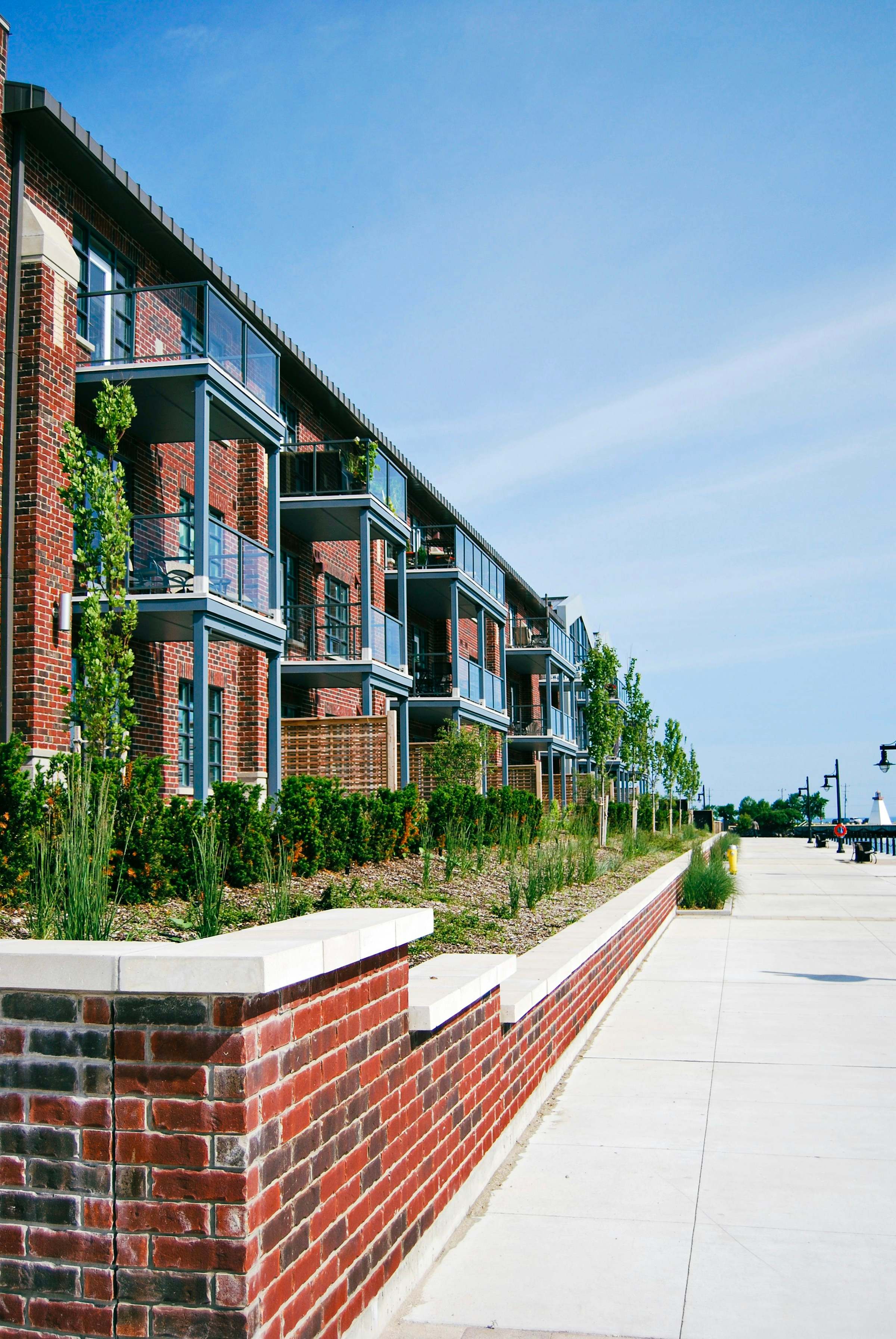 Brick apartment buildings with balconies along a landscaped walkway