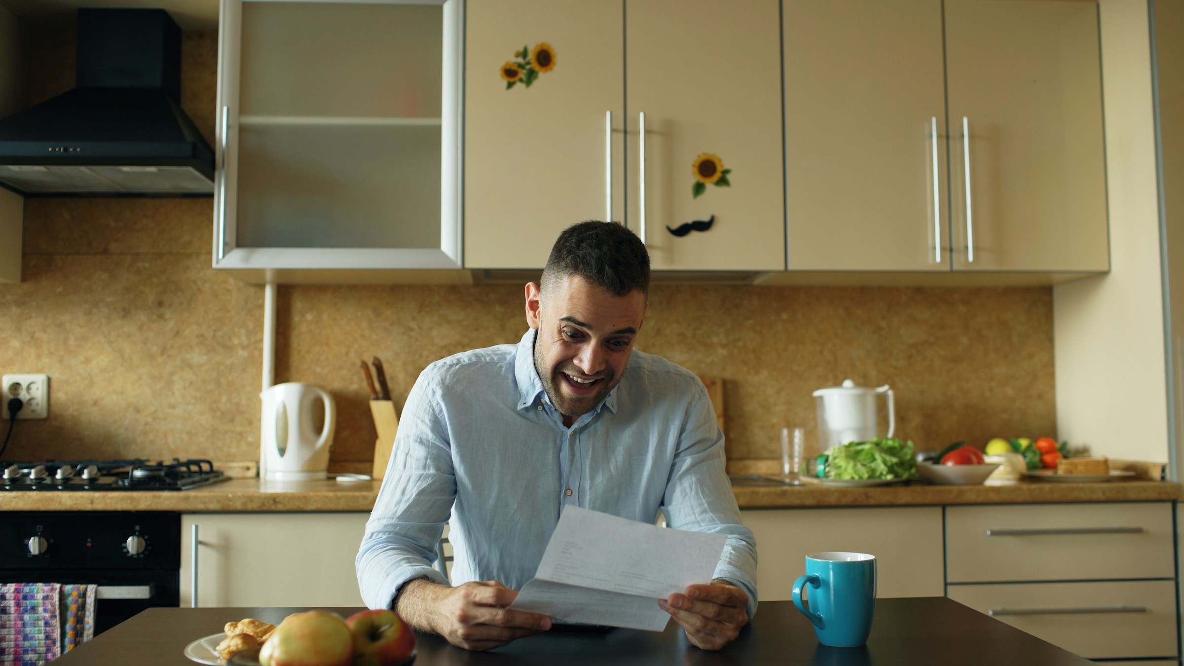 A man reading a letter at his kitchen table