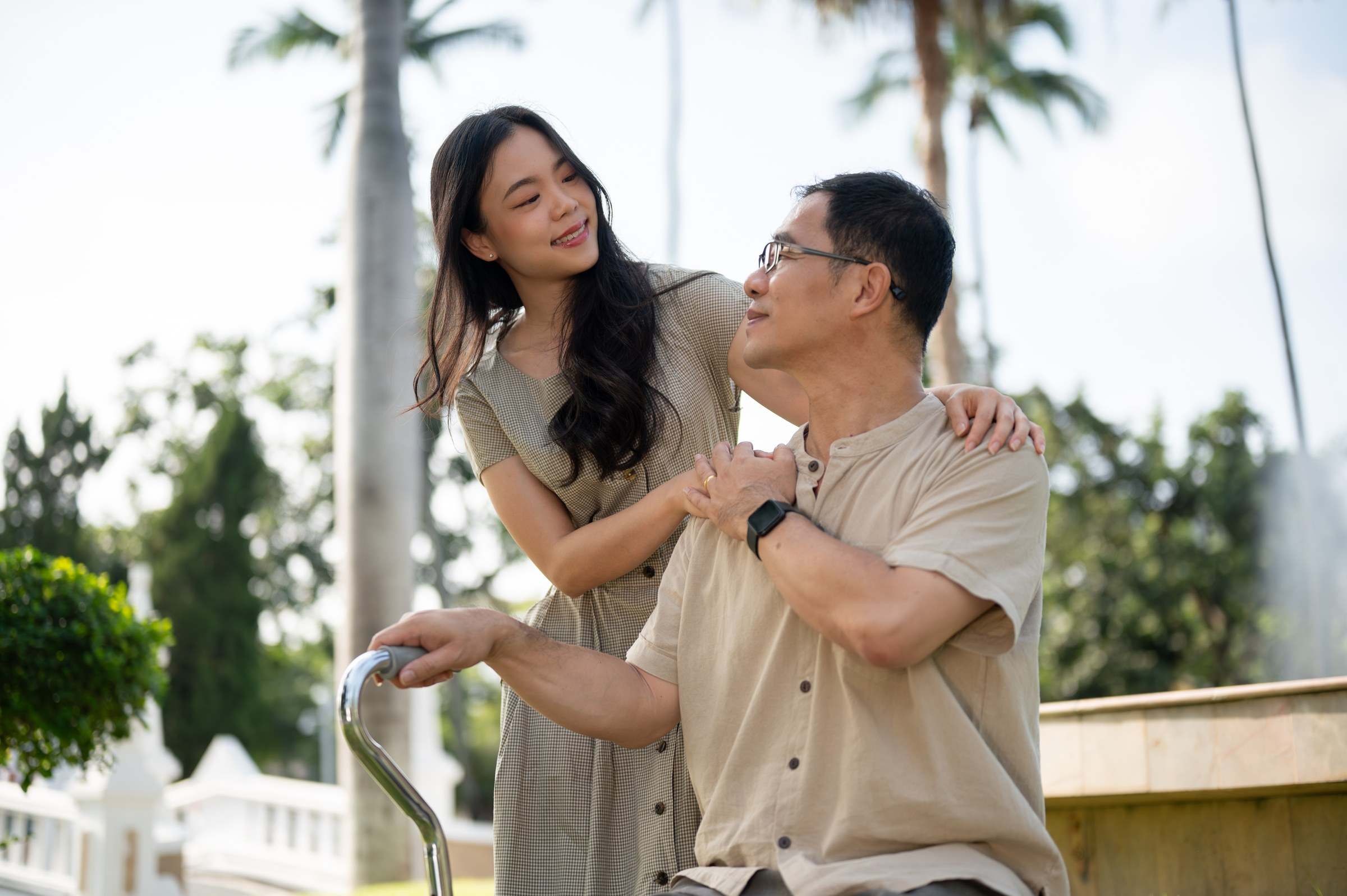 Daughter with her arm around her father in a sunny garden