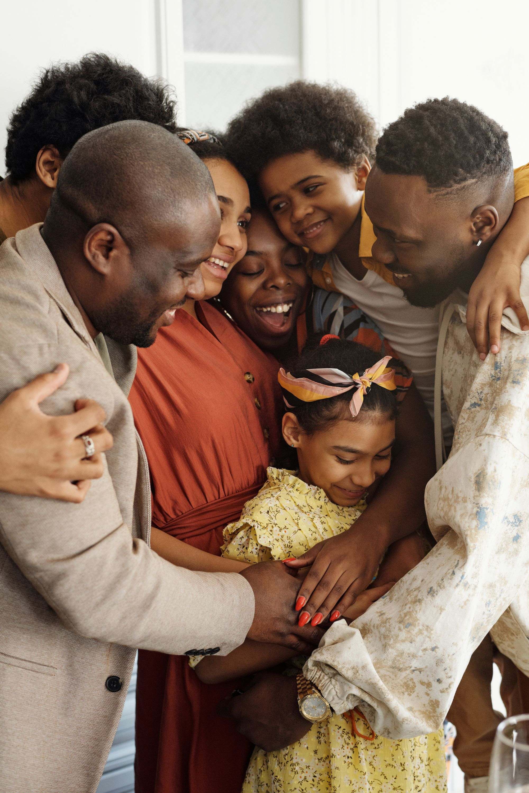 Black family sharing a warm group hug with a young girl in the middle