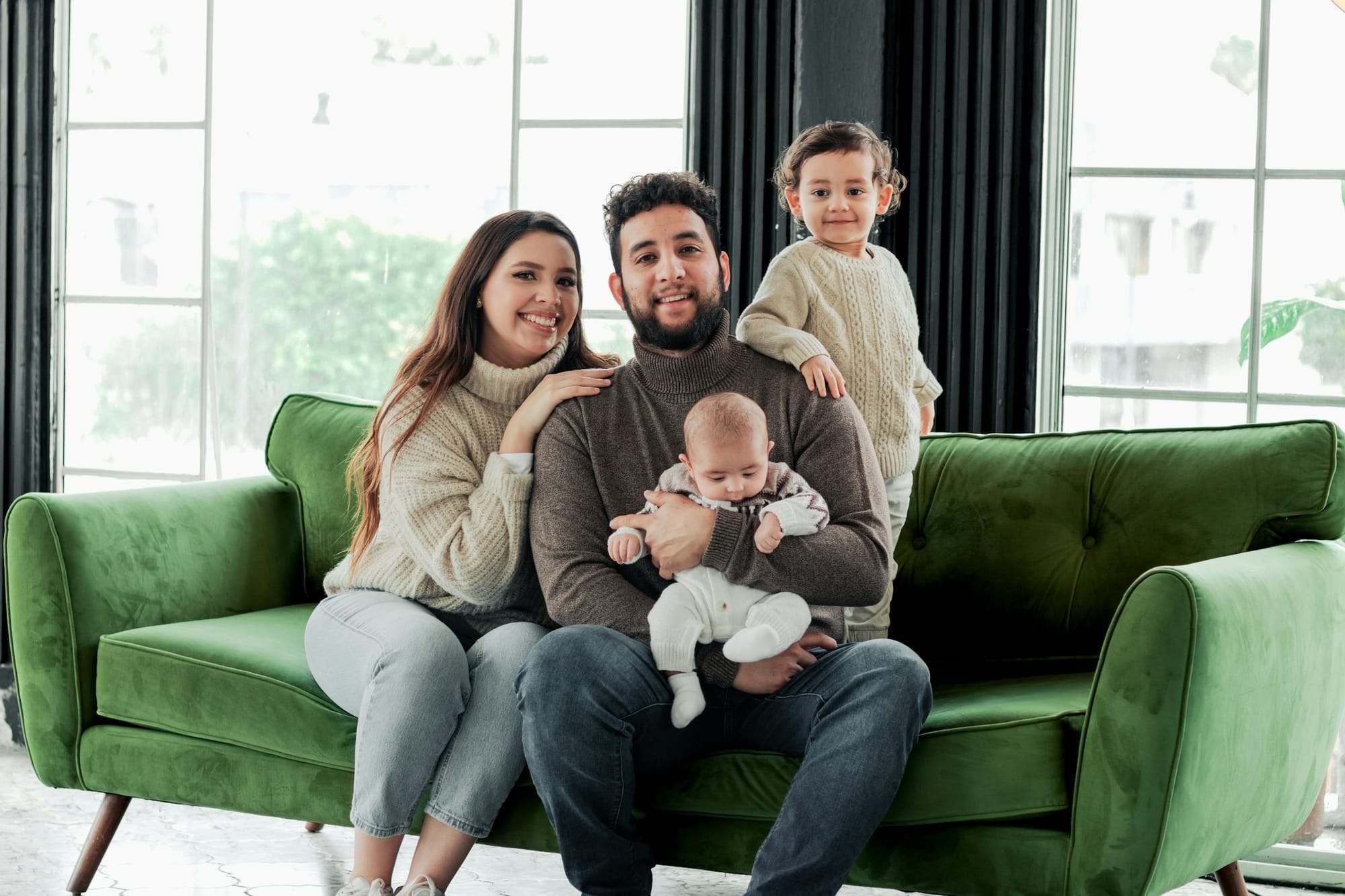 Parents and children together on a green sofa in a bright living room